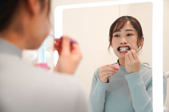 鏡の前でセルフホワイトニングをする女性